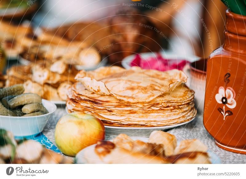 Dishes of the traditional Belarusian cuisine - pancakes and pickled cucumbers. Attribute of traditional folk celebration of Maslenitsa Belarussian Still life