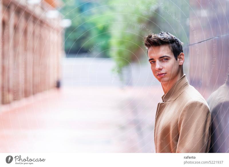 Portrait of stylish handsome young man with coat standing outdoors and leaning on wall. Adult Camera Caucasian Confidence Elegance Inspiration Jacket Leaning