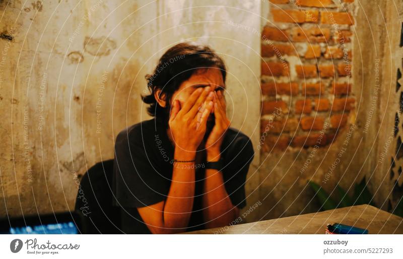 Portrait of asian young man stressed and hiding his face with two hands person emotion expression cover fear sad worried adult background depressed hide trouble