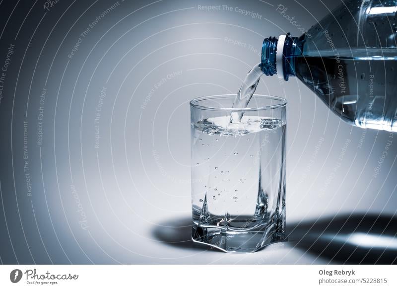 pouring water into a glass from a plastic bottle drink liquid beverage fresh transparent blue freshness healthy bubble refreshment clear flowing wet closeup