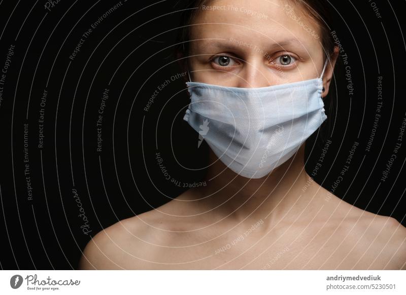 Young woman wearing a protective mask during the Coronavirus disease COVID-19 outbreak epidemic. Close up studio portrait on a black background. face protection