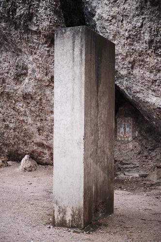 Strange concrete column or concrete block stands on the path in front of gray rocks Concrete column Concrete cuboid Column Cuboid Gray off Stand Puzzle puzzling