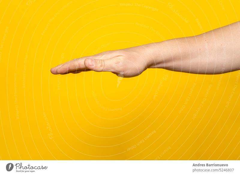 Strong man's arm with palm outstretched upside down isolated on yellow background. hand closeup caucasian finger adult person white human concept people male