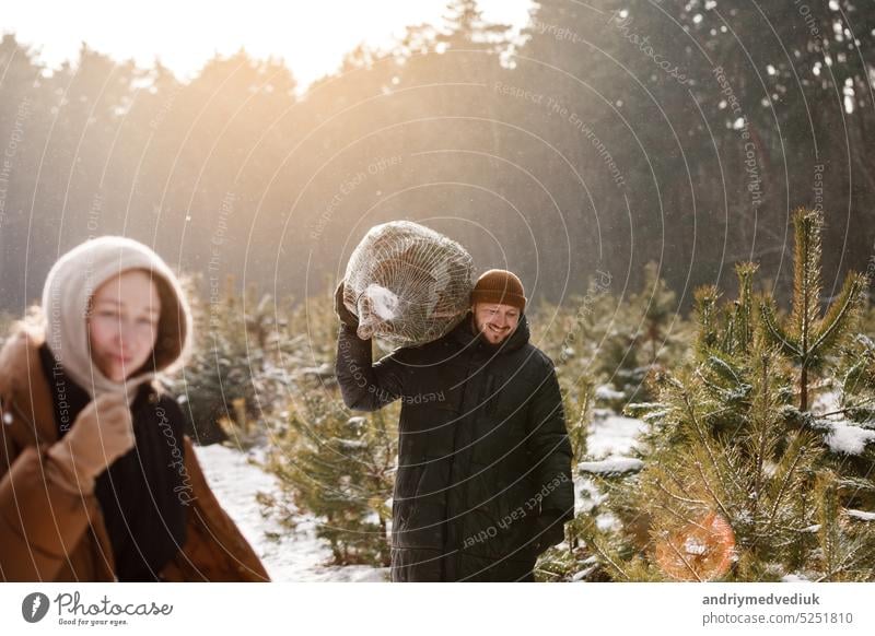 Love romantic young couple woman, man in snowy winter forest with fir tree. Walking, having fun, laughing in stylish warm clothes. Snow lovestory. Romantic date, weekend. Happy Christmas and New Year