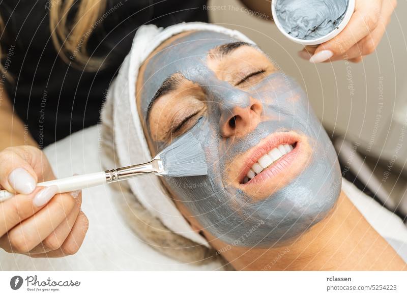 cosmetologist making dead sea mud mask on face for rejuvenation on the cosmetology salon. relaxing skin care cosmetic surgery cosmetician dermatologist therapy