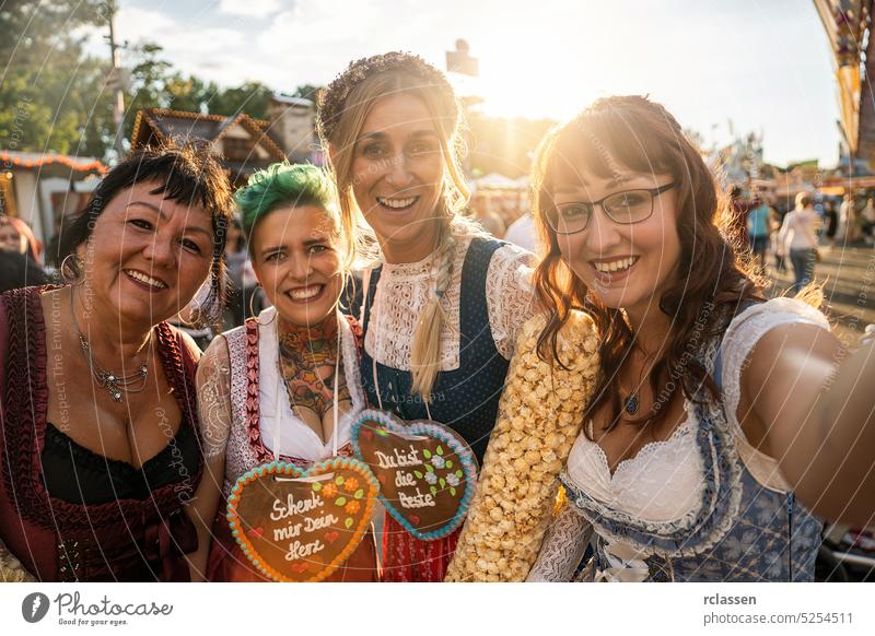 Girlfriends in traditional Bavarian clothes dirndl or tracht with Schenk mir dein Herz, Du bist die beste (German: Give me your heart, you are best ) written on gingerbreads heart on Oktoberfest