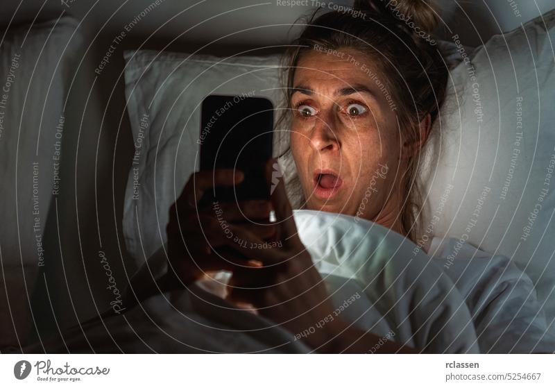 Shocked woman using smartphone in bed. Insomnia and stalking concept image happy single exchange bed pillow sleep insomnia night anxiety loneliness people