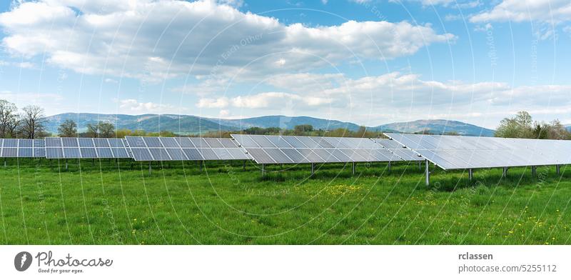 Solar panel under blue sky with sun. Green grass and cloudy sky. Alternative energy concept image solar clean power electric photovoltaic field light green