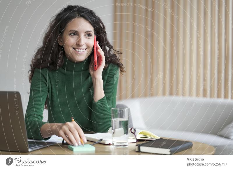 Smiling business lady using mobile to communicate and receive orders, writing info on sticky note businesswoman talk phone work home laptop call client discuss