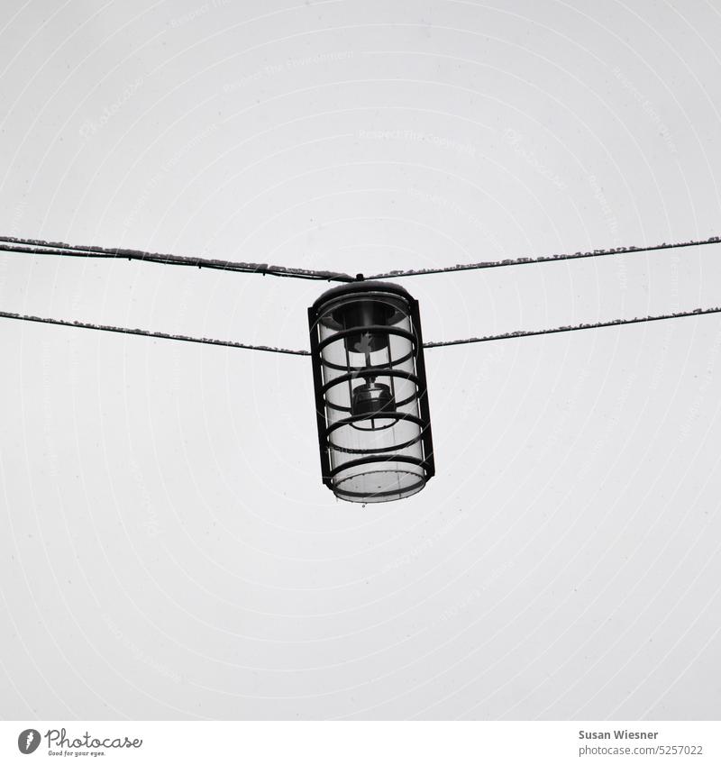 Street light/street lamp hanging on two cables in the shape of a cylinder in winter Cylinder Exterior shot Street lighting Lighting Lantern lighting units
