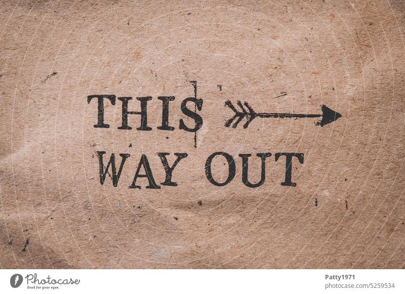 This way out. Stamped text on crumpled wrapping paper. Way out Exit route Word Text Arrow Paper Grunge Brown Wrapping paper Direction exit Escape route