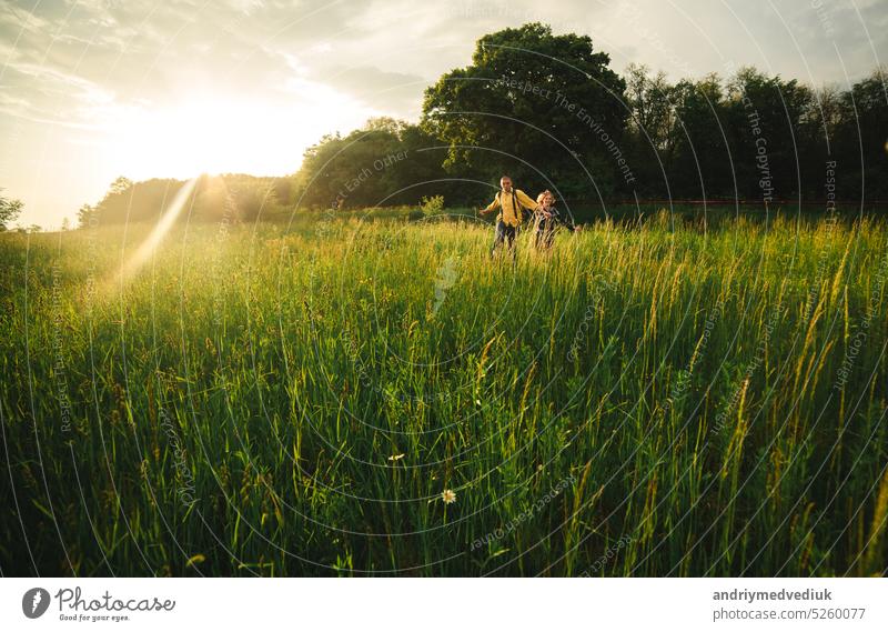 Loving hipster couple walking in the field, kissing and holding hands, hugging, lying in the grass in the summer at sunset. valentines day man love relationship