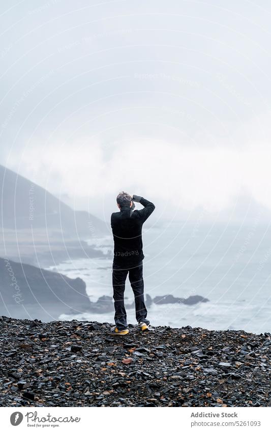 Anonymous photographer taking photo of sea man take photo cliff photo camera nature hobby photography moment iceland europe fog travel adventure tourism memory