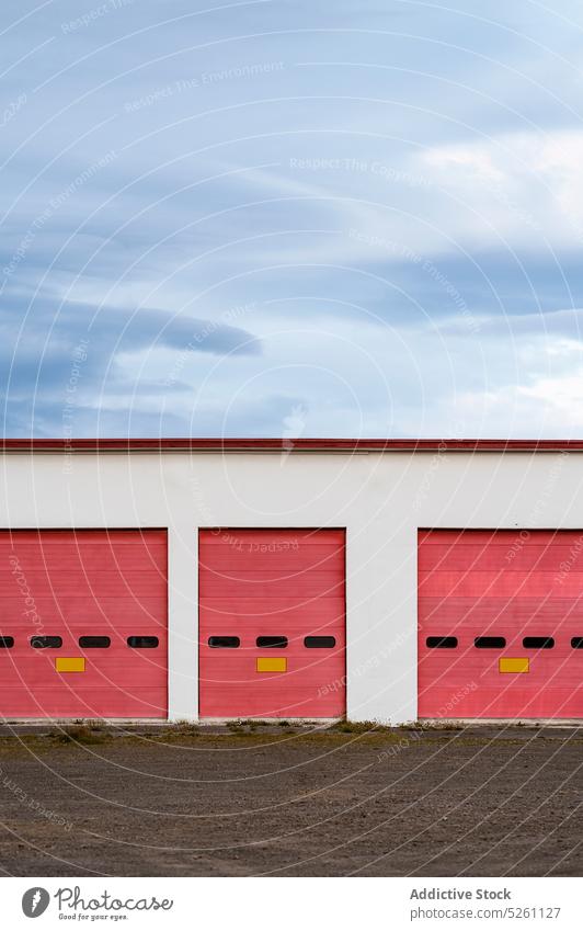 Garage with red gates under cloudy sky countryside storage garage exterior modern building facade minimal entrance iceland europe industrial blue sky industry