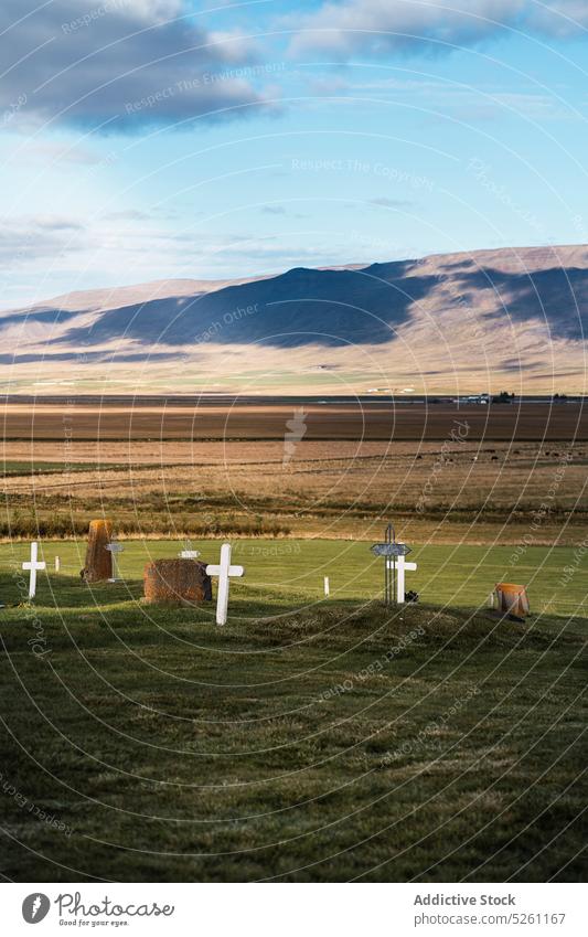 Catholic cemetery in countryside field graveyard landscape tombstone grassy gravestone valley picturesque scenery cloudy nature iceland blue sky sunlight