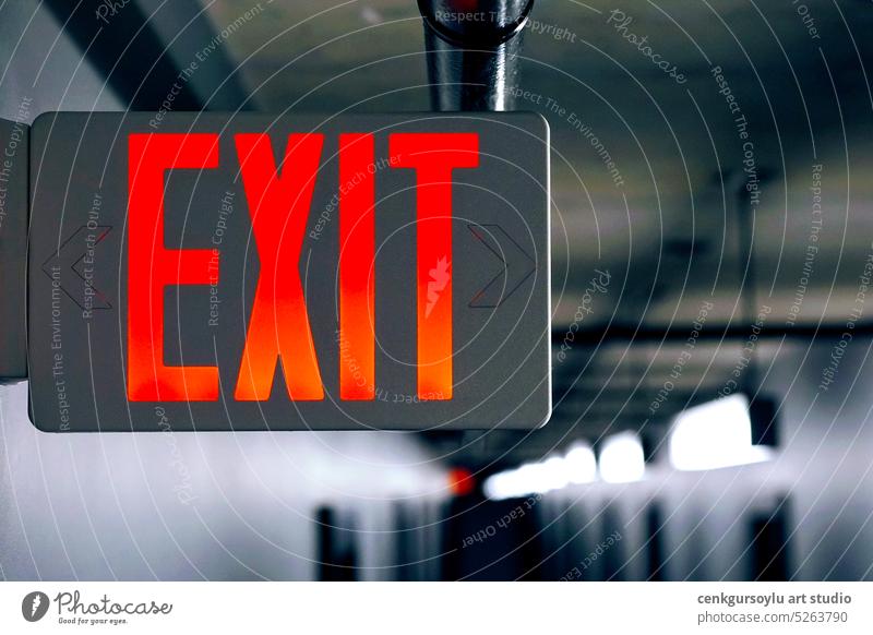 Lighted glowing red emergency exit signs in an office hallway with arrows pointing the way out of the building. background banner blurry breastfeeding