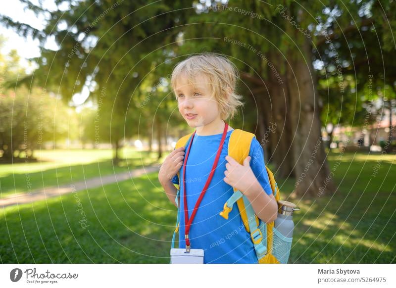 Elementary student boy with backpack, bottle of water and name badge on his neck goes to school. Happy child is waiting of school bus. tag elementary icon id
