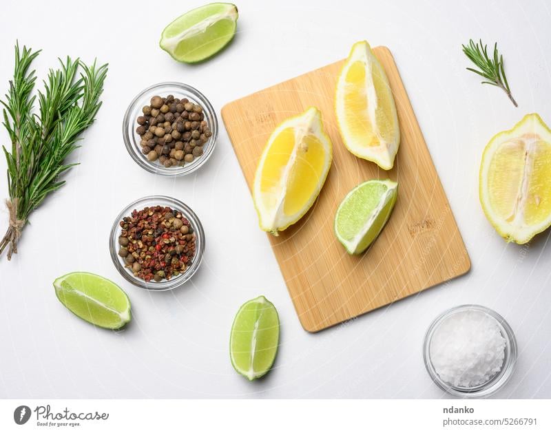 Various lemon and lime slices on a wooden board. Salt, spices and rosemary branches on a white background, top view fresh citrus salt pepper fruit food yellow