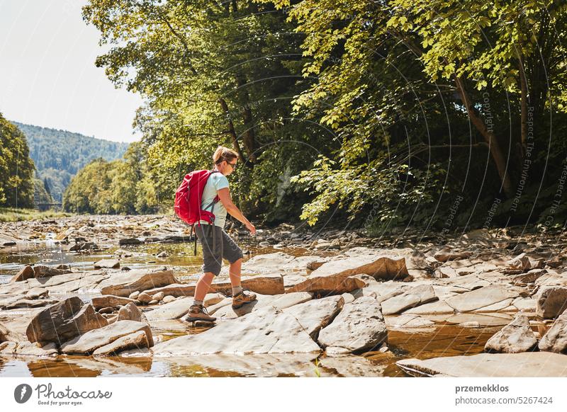 Woman with backpack hiking in mountains, spending summer vacation