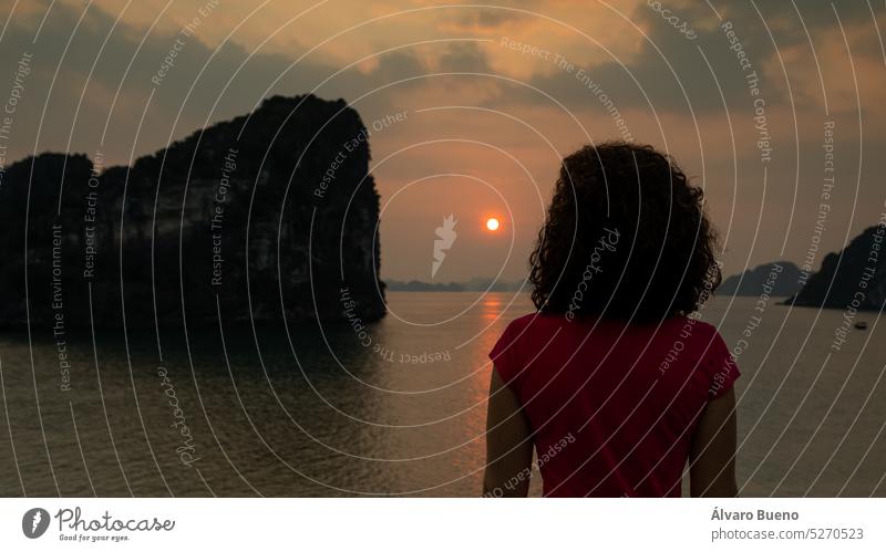 A woman, a western tourist, enjoys the sunset over the karst seascape of Ha Long Bay in Vietnam, Southeast Asia northern Vietnam karst formations Vinh