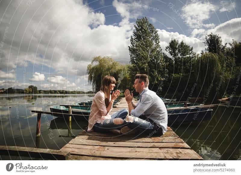 Ideal moment.. Beautiful young couple embracing and smiling while sitting on the pier activity beautiful nature romantic people summer travel human love