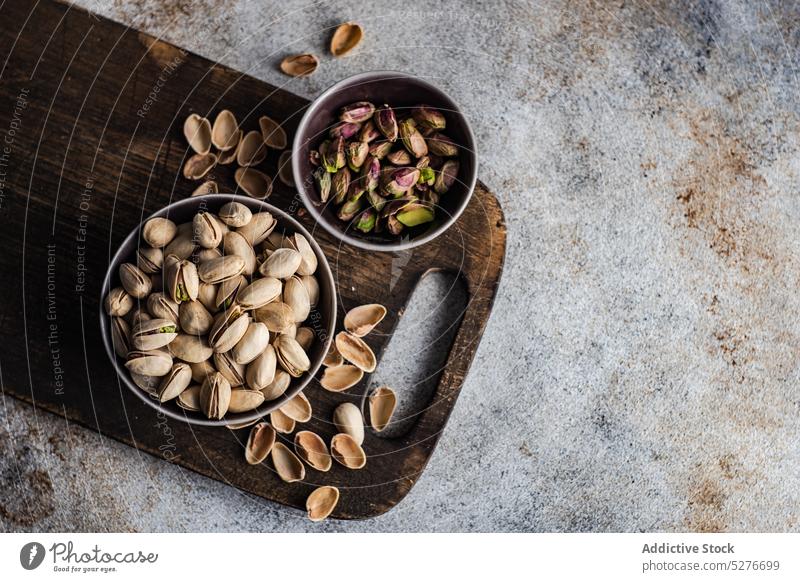 Bowls with different kinds of nuts almond pistachio hazelnut rustic raw nutrient seed ketogenic table dried crunchy wooden nutshell nutrition heap cutting board