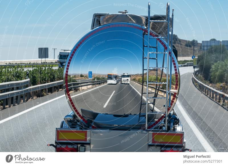 Rear of a tanker truck with a mirror effect, where a truck and a bus are reflected behind it. trailer transport reflection back vehicle industry speed highway