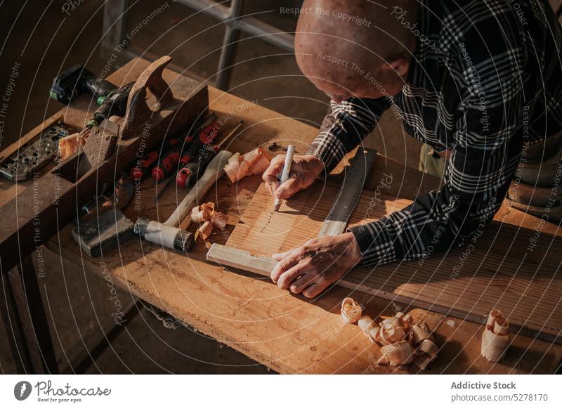 Senior woodworker measuring wooden board in workshop man measure ruler craft carpenter craftsman pencil detail senior elderly carpentry joinery professional job