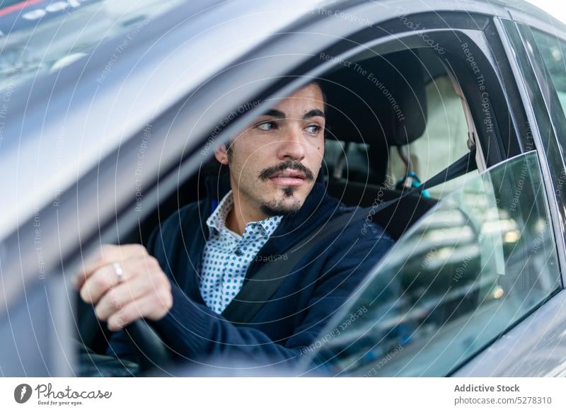 Young Hispanic male driver sitting in modern car man concentrate vehicle steering wheel confident city window auto serious young hispanic ethnic brunet beard