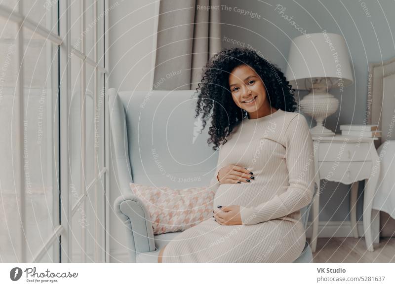 Pregnant caucasian woman relaxing at home. Young expectant mother strokes  her pregnant belly and thinks about the baby childbirth. - a Royalty Free  Stock Photo from Photocase