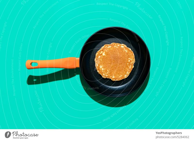 Pancake in a iron cast pan, top view on a green colored background above american baked bakery breakfast bright brunch concept copy space cuisine cut out