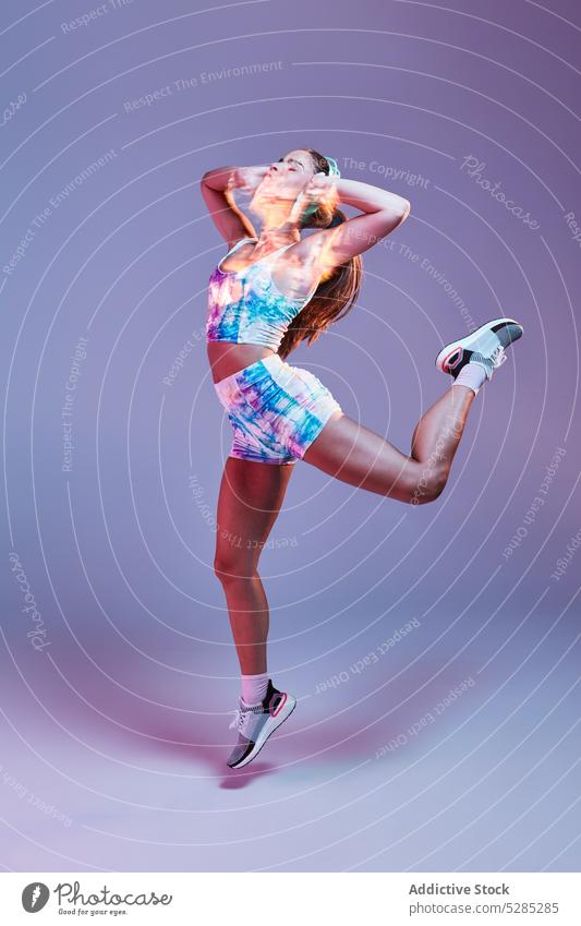 Woman jumping while listening to music on headphones woman dance energy motion touch studio shot female meloman tune sound young healthy lifestyle activewear