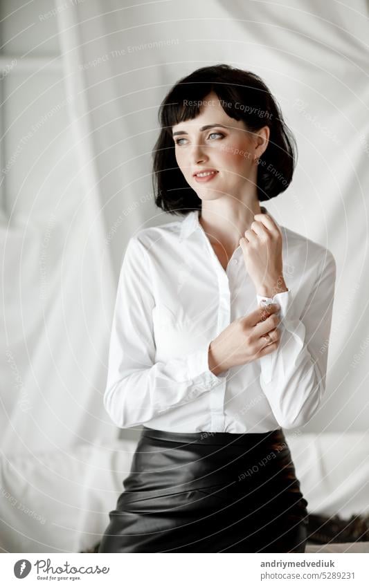 Confident happy attractive business woman. elegant Girl in white shirt and leather skirt sitting at home office beautiful black fashion caucasian clothes studio
