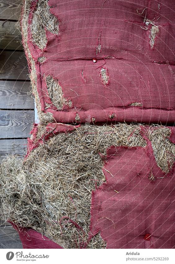 Old tattered cushions filled with hay Bolster Hay Broken shattered torn holes Cloth Red seat cushions Wood Wooden floor Wooden boards