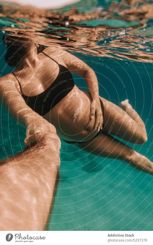 Anonymous young woman in bikini lounging in pool - a Royalty Free
