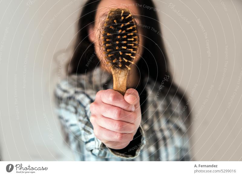 Woman showing to the camera a hairbrush full of hairs. Hair falling concept. Baldness, female alopecia. Hair and hairstyles Hair brushing Hairbrush