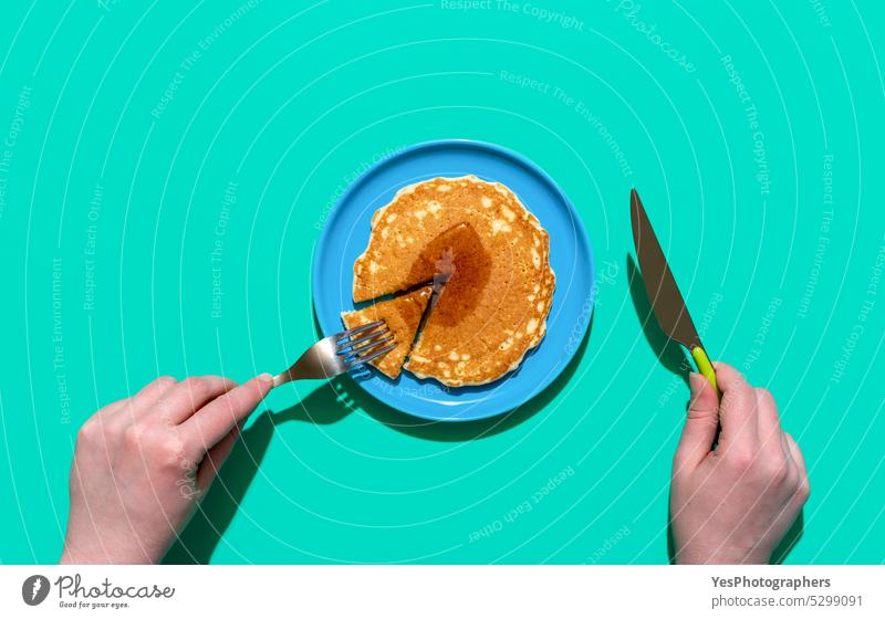 Eating pancake with maple syrup, above view. Pancake on a plate on minimalist on a green background american baked blue breakfast bright brunch color copy space