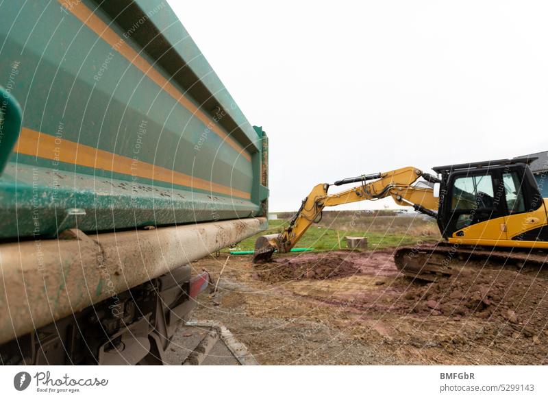 On the construction site - earthworks to prepare a building plot for house construction with excavator and truck Construction site House building Building lot