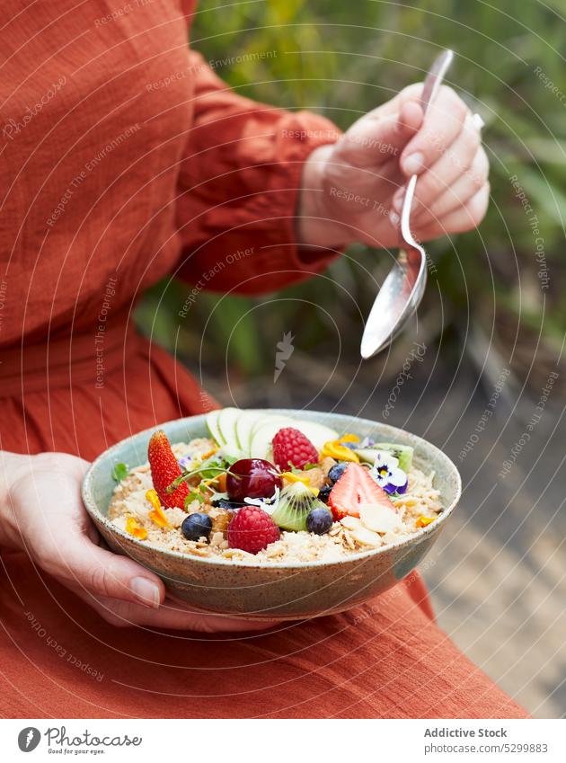 Woman with bowl of cereal with fruit and berries woman oatmeal berry cherry strawberry raspberry blueberry kiwi apple female eat breakfast porridge food tasty