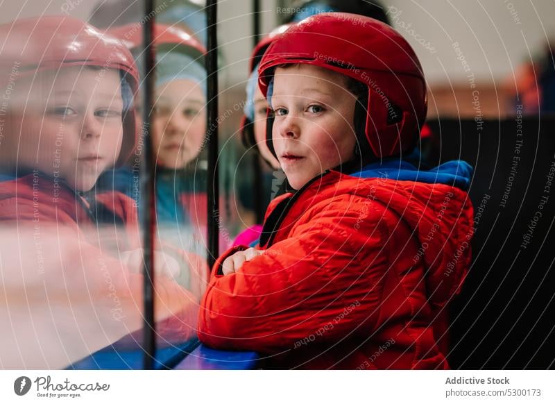 Pensive boy looking at ice rink winter kid safety thoughtful fence protect cold pensive serious helmet season child activity sport outerwear childhood frozen