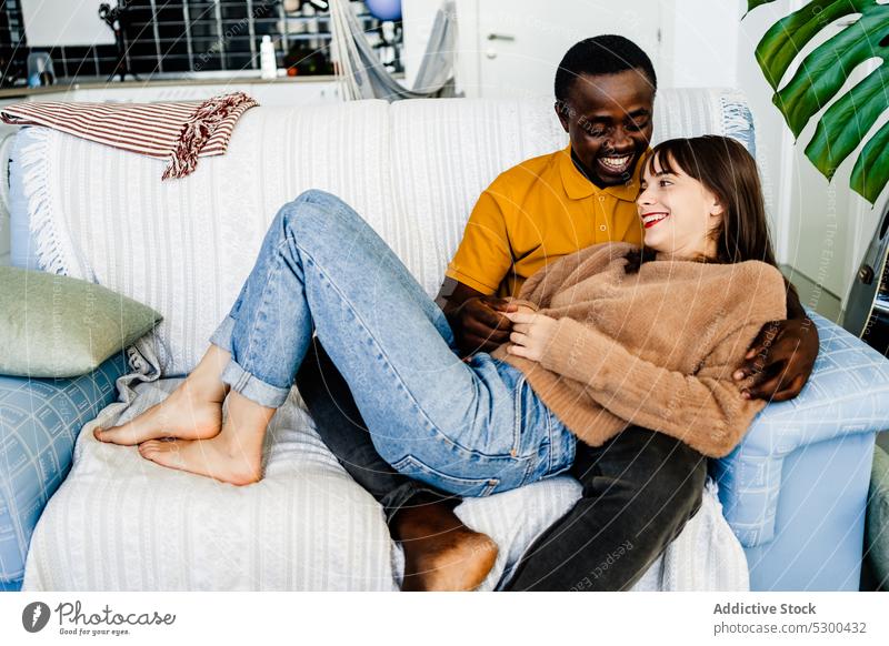 Diverse loving couple resting on sofa love together relationship cheerful spend time smile relax bonding home happy multiethnic multiracial living room diverse