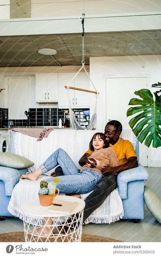 Diverse loving couple resting on sofa love together relationship cheerful spend time smile relax bonding home happy multiethnic multiracial living room diverse