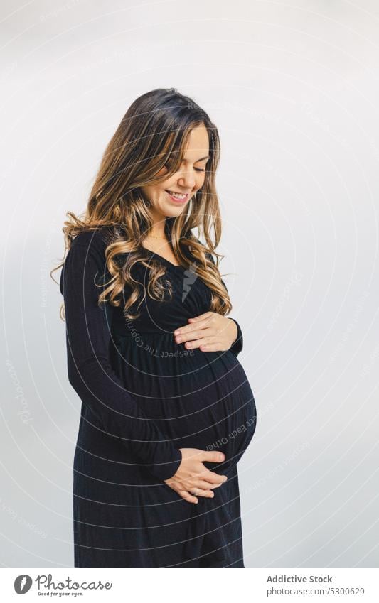 Calm pregnant woman touching baby bump happy love caress touch belly smile await carry prenatal expect female young abdomen feminine sensual childbearing