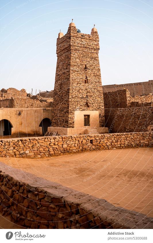 Ancient mosque with stone fence architecture ancient heritage culture historic religion building old aged islam sahara mauritania africa cloudless blue sky