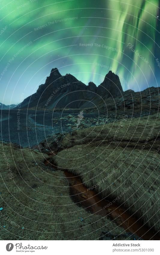 Picturesque view of black sand beach under sky with polar light mountain aurora borealis water stockness iceland shore nature coast vestrahorn Krossanesfjall