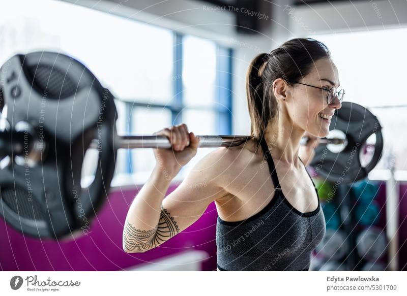 Young woman working out with a barbell at the gym wellness wellbeing bodybuilder sporty lifting biceps muscles bodybuilding people muscular adult person