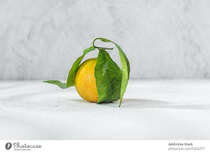 Orange mandarin on white table orange citrus tangerine verdant stem leaf leaves fruit meal food organic healthy raw fresh ripe juicy sweet vitamin natural