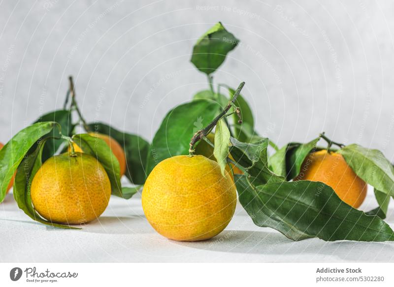 Orange mandarin on white table orange citrus tangerine verdant stem leaf lie cleaned leaves fruit meal food organic healthy raw fresh ripe juicy sweet vitamin