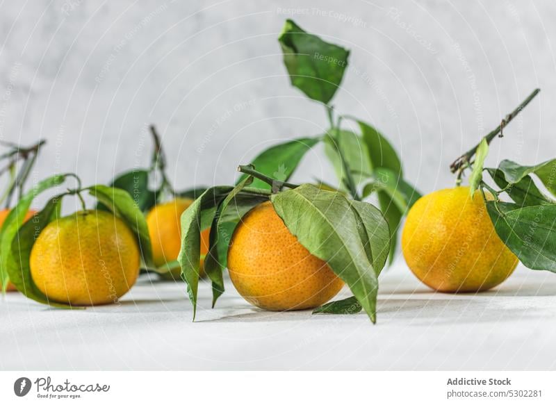 Orange mandarin on white table orange citrus tangerine verdant stem leaf lie cleaned leaves fruit meal food organic healthy raw fresh ripe juicy sweet vitamin