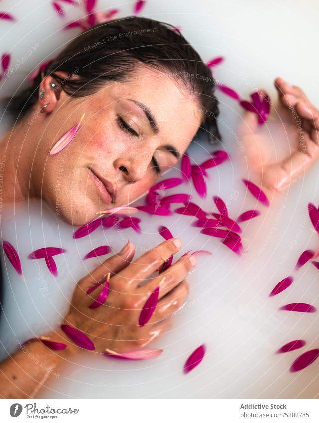 Calm woman taking bath with pink petals and milk flower bathtub peaceful hygiene spa skin care sensual female wellness rest chill sleep natural water fresh